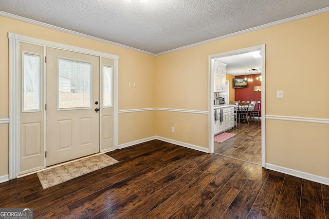 foyer entrance featuring a textured ceiling, dark wood finished floors, ornamental molding, and baseboards