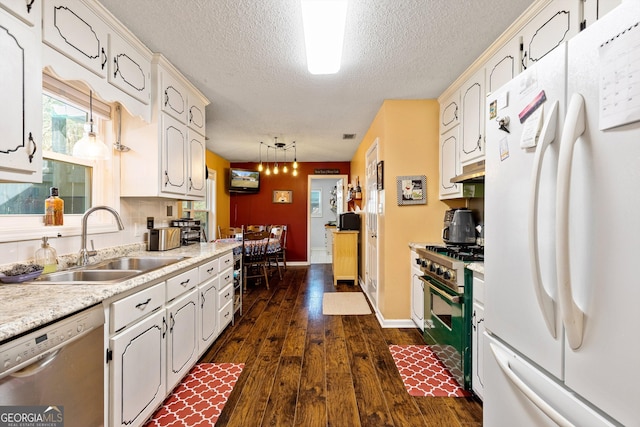 kitchen featuring a sink, dishwasher, freestanding refrigerator, gas range, and dark wood-style floors
