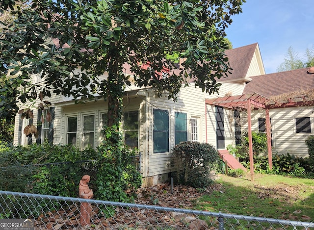 view of property exterior featuring fence and a pergola