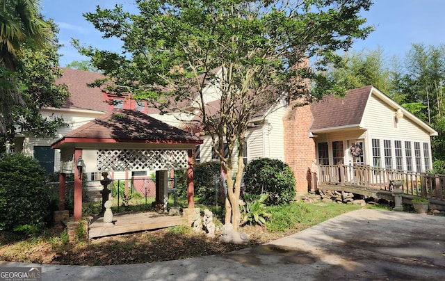 view of front facade with a gazebo, a shingled roof, and a wooden deck