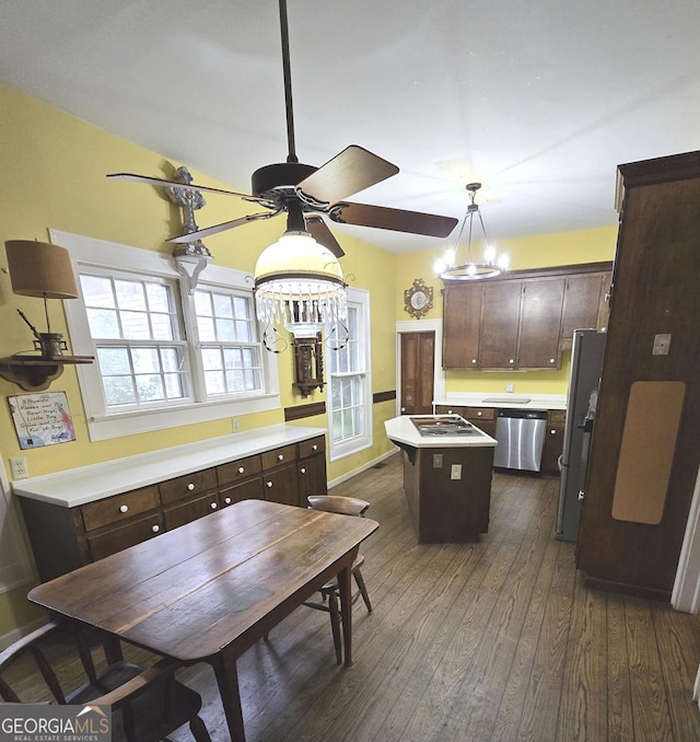 kitchen featuring appliances with stainless steel finishes, a center island, dark brown cabinets, light countertops, and dark wood-style floors