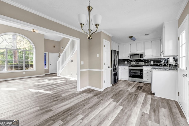 60 Whispering Pine Ct, Covington, GA 30016 - kitchen featuring stainless steel appliances, open floor plan, backsplash, light wood finished floors, and white cabinets