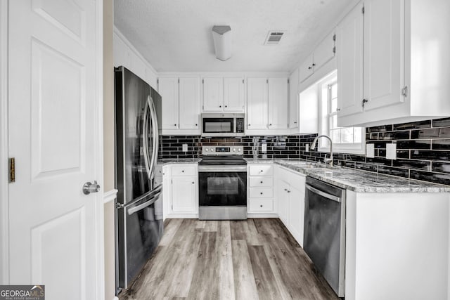 60 Whispering Pine Ct, Covington, GA 30016 - kitchen with stainless steel appliances, a sink, decorative backsplash, light wood finished floors, and white cabinets