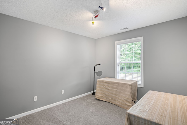 bedroom with baseboards, carpet, a textured ceiling, and visible vents