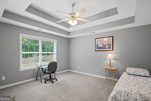 bedroom with carpet flooring, a tray ceiling, visible vents, and baseboards