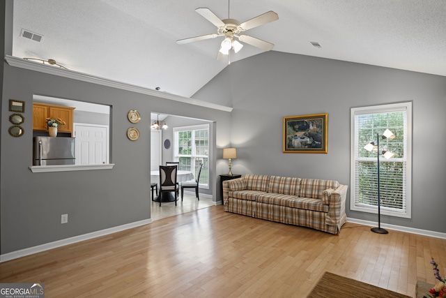 living room featuring ceiling fan, baseboards, lofted ceiling, light wood-type flooring, and visible vents