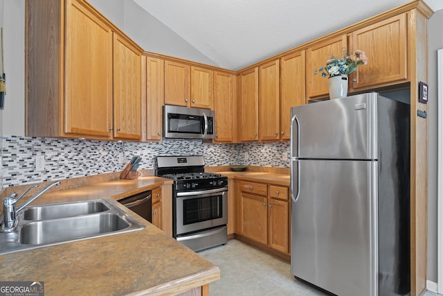 kitchen with a textured ceiling, tasteful backsplash, a sink, appliances with stainless steel finishes, and vaulted ceiling