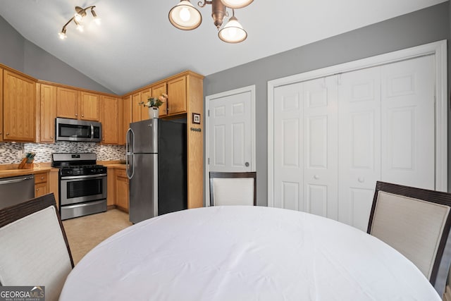 kitchen with a notable chandelier, light countertops, stainless steel appliances, lofted ceiling, and backsplash