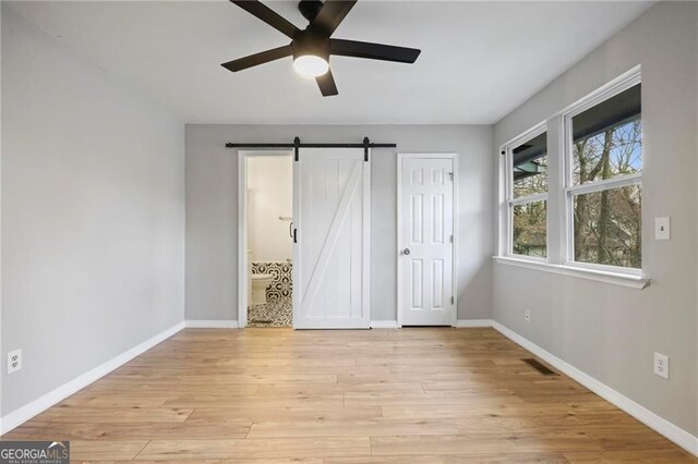 1350 Overlook Cv SE, Smyrna, GA 30080 - unfurnished bedroom with light wood-style floors, baseboards, a barn door, and visible vents
