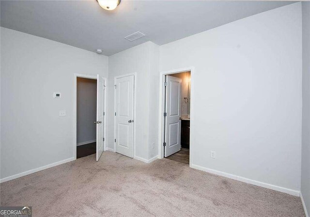 2539 Hedgeway Cir, Kennesaw, GA 30144 - unfurnished bedroom with baseboards, carpet, connected bathroom, and visible vents