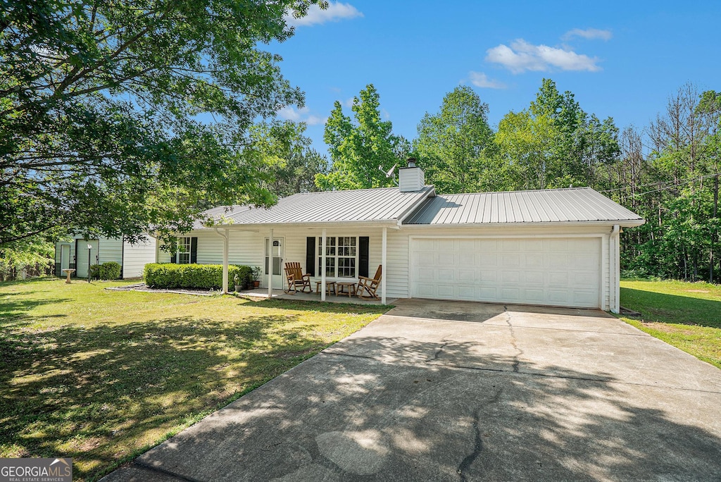 696 Swann Rd, Jefferson, GA 30549 - ranch-style house featuring an attached garage, driveway, a front lawn, a chimney, and metal roof