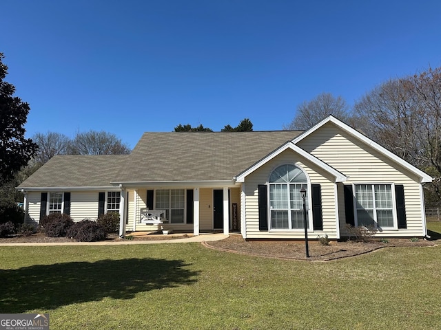ranch-style house featuring a porch, roof with shingles, and a front yard