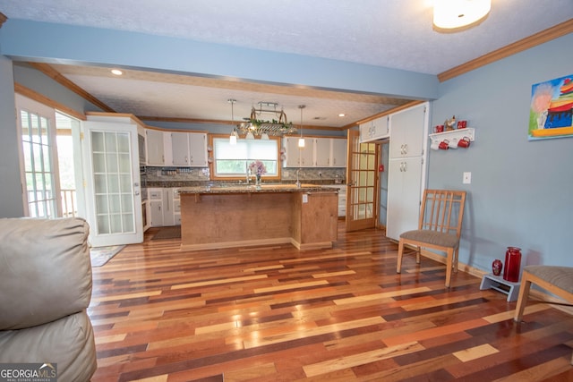 kitchen with crown molding, open floor plan, tasteful backsplash, and light wood-style floors