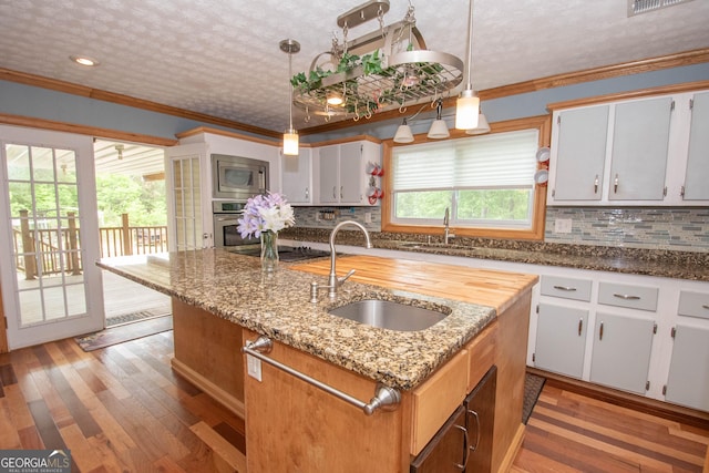 kitchen featuring a sink, a kitchen island with sink, stainless steel appliances, and light wood finished floors