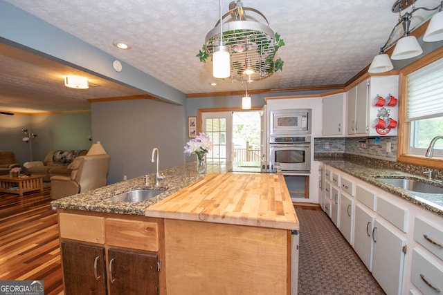 kitchen with a sink, white cabinets, backsplash, and an island with sink