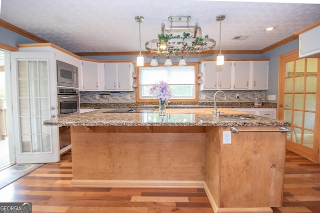 kitchen with a sink, stainless steel appliances, white cabinetry, decorative backsplash, and ornamental molding