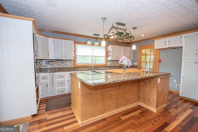 kitchen with light wood-style floors, ornamental molding, light stone counters, and tasteful backsplash