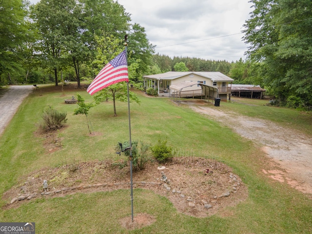 view of front facade with driveway, a wooden deck, a front yard, and a carport