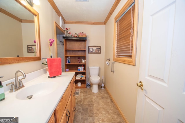 bathroom featuring stone finish flooring, vanity, baseboards, toilet, and ornamental molding