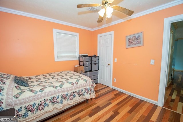bedroom featuring crown molding, a ceiling fan, baseboards, wood finished floors, and visible vents