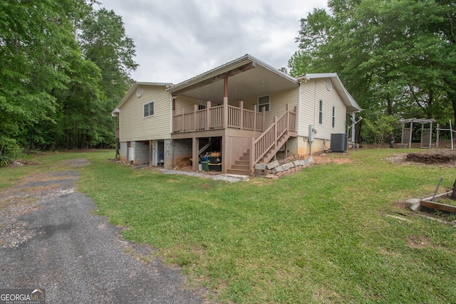 exterior space featuring driveway, a yard, central AC, and stairway