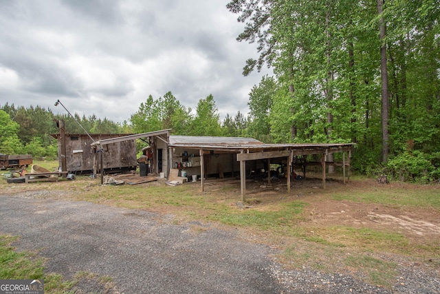 exterior space with a detached carport, an outdoor structure, and a view of trees