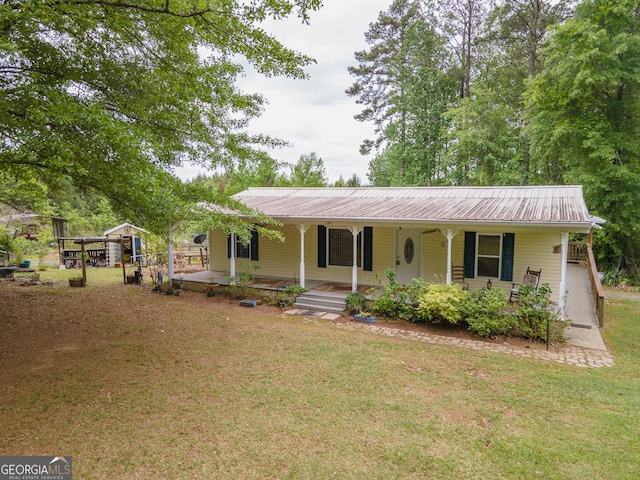 view of front of property featuring covered porch, metal roof, and a front lawn