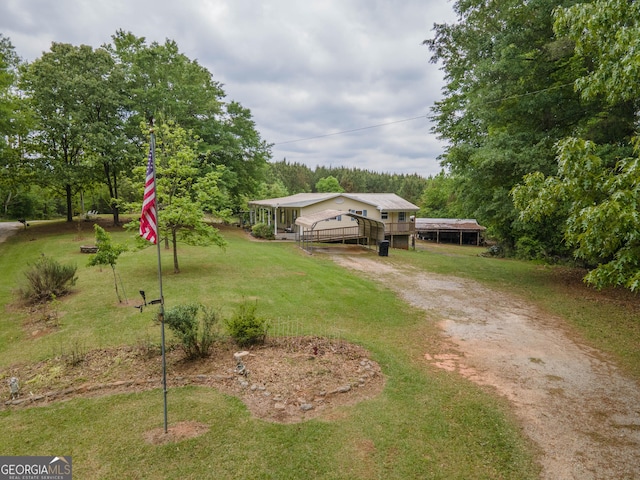 view of yard featuring dirt driveway and a detached carport