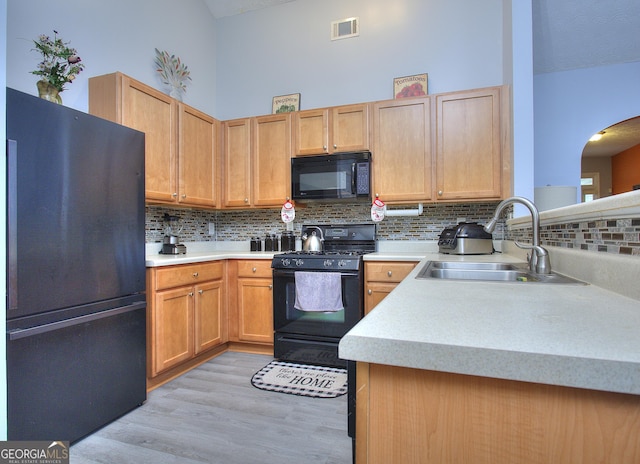 kitchen with backsplash, visible vents, a sink, black appliances, and light wood-style floors