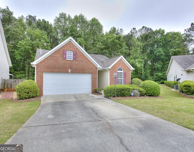 view of front of home featuring fence, roof with shingles, brick siding, a front yard, and driveway