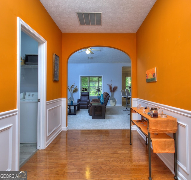 hall featuring arched walkways, a textured ceiling, and visible vents