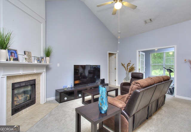 carpeted living room featuring visible vents, baseboards, high vaulted ceiling, a tile fireplace, and a ceiling fan