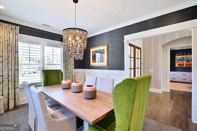dining space featuring wainscoting, a chandelier, wood finished floors, visible vents, and ornamental molding