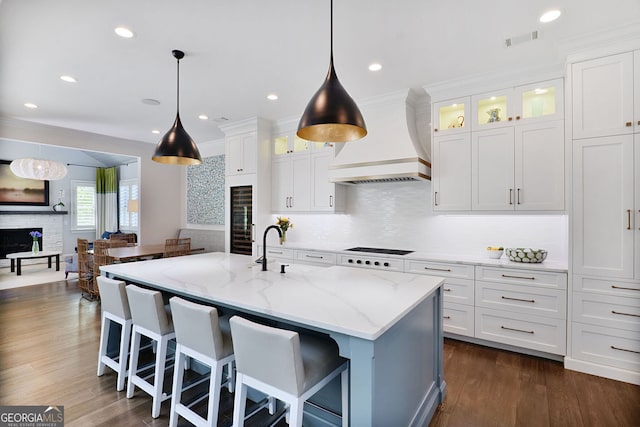 kitchen with white cabinetry, wine cooler, premium range hood, and a fireplace