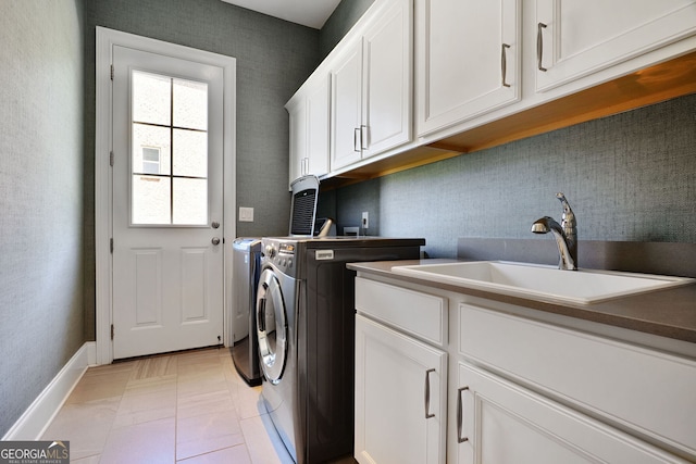 washroom with a sink, baseboards, washing machine and dryer, and cabinet space