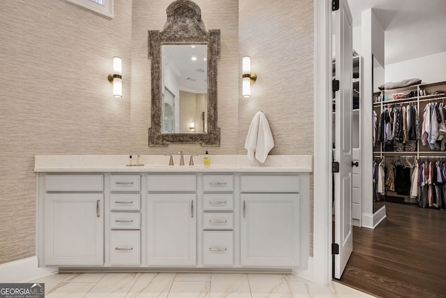 bathroom with a spacious closet, marble finish floor, and vanity