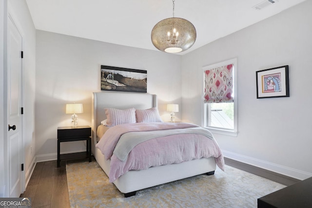 bedroom featuring baseboards, a notable chandelier, wood finished floors, and visible vents