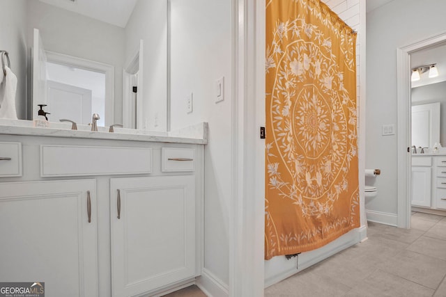 bathroom featuring vanity, baseboards, tile patterned floors, and toilet