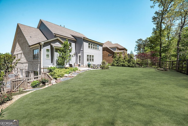 rear view of property featuring a fenced backyard, a patio, and a yard