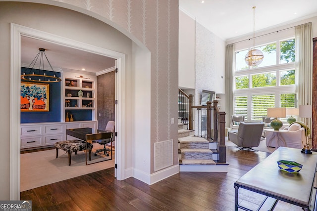 hallway with visible vents, ornamental molding, dark wood-style flooring, stairs, and built in features