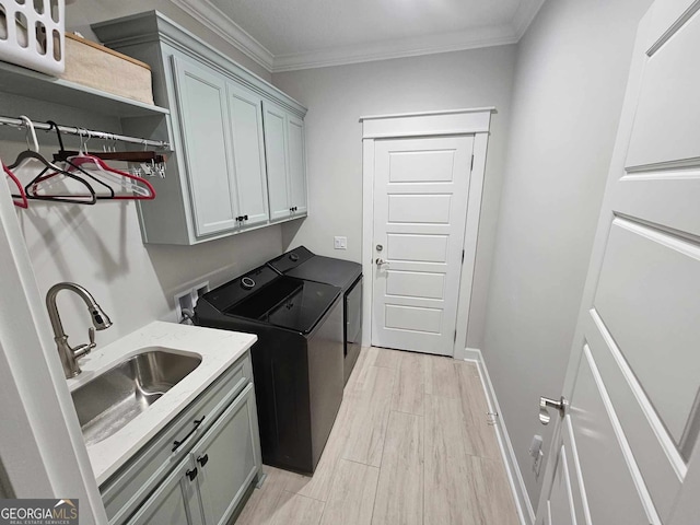 laundry area with crown molding, separate washer and dryer, a sink, cabinet space, and light wood finished floors