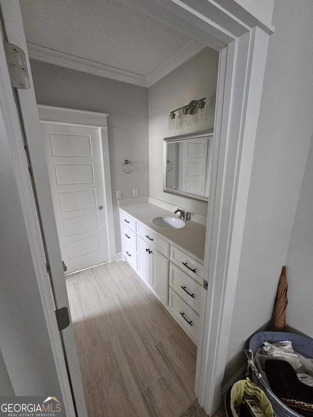 bathroom with crown molding, wood finished floors, and vanity