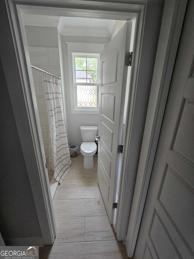 full bathroom with wood finished floors, ornamental molding, a stall shower, and toilet