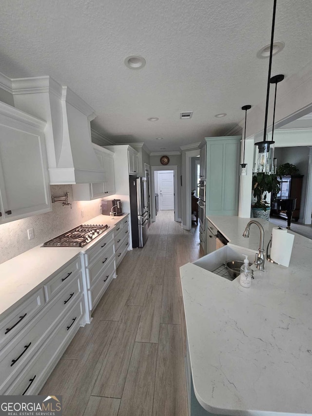 kitchen featuring a sink, a textured ceiling, stainless steel appliances, tasteful backsplash, and visible vents