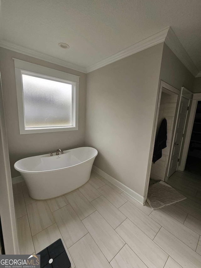 bathroom featuring baseboards, ornamental molding, and a freestanding bath