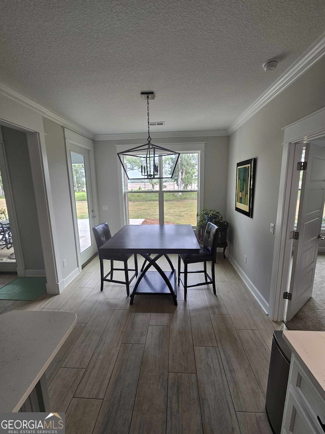 dining area featuring baseboards, ornamental molding, a textured ceiling, and wood finished floors