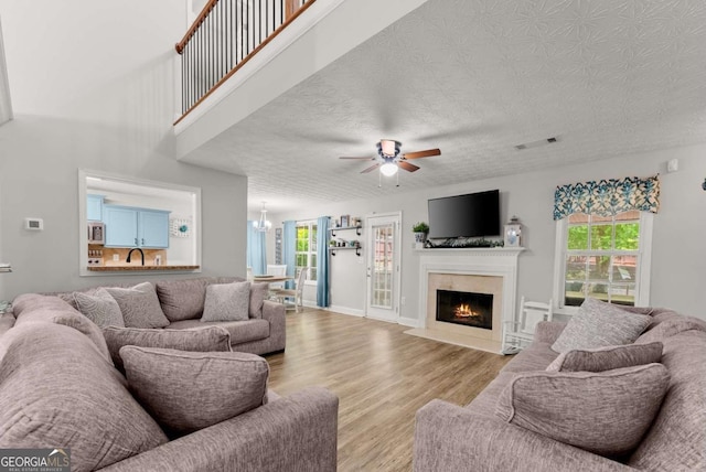 1338 Jefferson Station Rd, Jefferson, GA 30549 - living room featuring ceiling fan, wood finished floors, plenty of natural light, a fireplace with flush hearth, and a textured ceiling