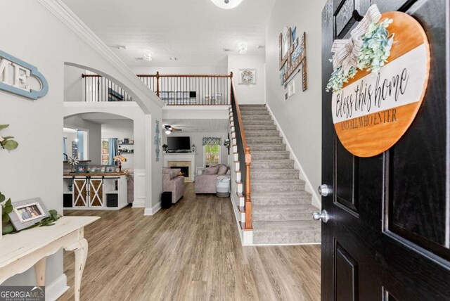 1338 Jefferson Station Rd, Jefferson, GA 30549 - foyer entrance featuring stairs, a warm lit fireplace, wood finished floors, ceiling fan, and crown molding