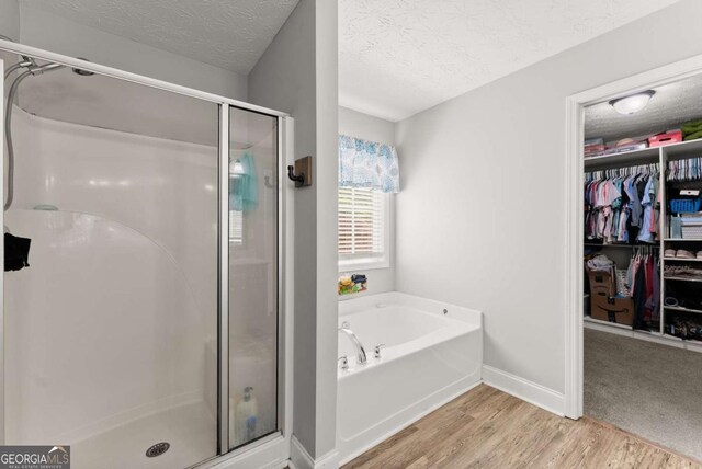 1338 Jefferson Station Rd, Jefferson, GA 30549 - full bath with a stall shower, wood finished floors, a garden tub, a textured ceiling, and a walk in closet