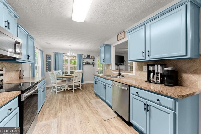 1338 Jefferson Station Rd, Jefferson, GA 30549 - kitchen with appliances with stainless steel finishes, blue cabinets, light wood-style flooring, tasteful backsplash, and a chandelier